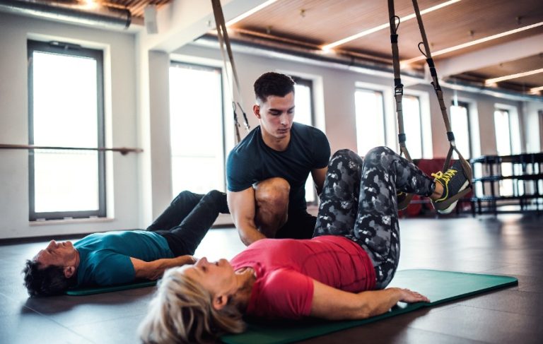 Une femme effectue un exercice de pilates sur un tapis bleu, concentrée sur sa posture et sa respiration