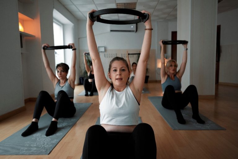 Une femme pratique des mouvements de base de pilates sur un tapis, concentrée sur la respiration et l’alignement de son corps