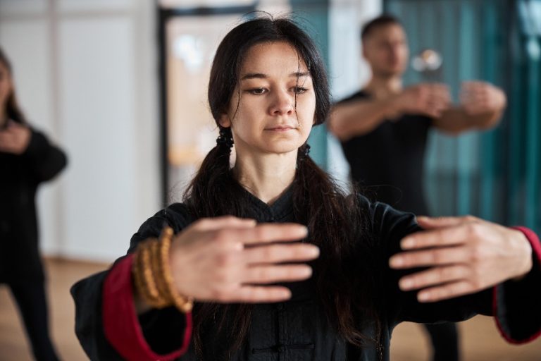 Groupe de personnes pratiquant le Qi Gong dans un parc, effectuant des mouvements lents et harmonieux