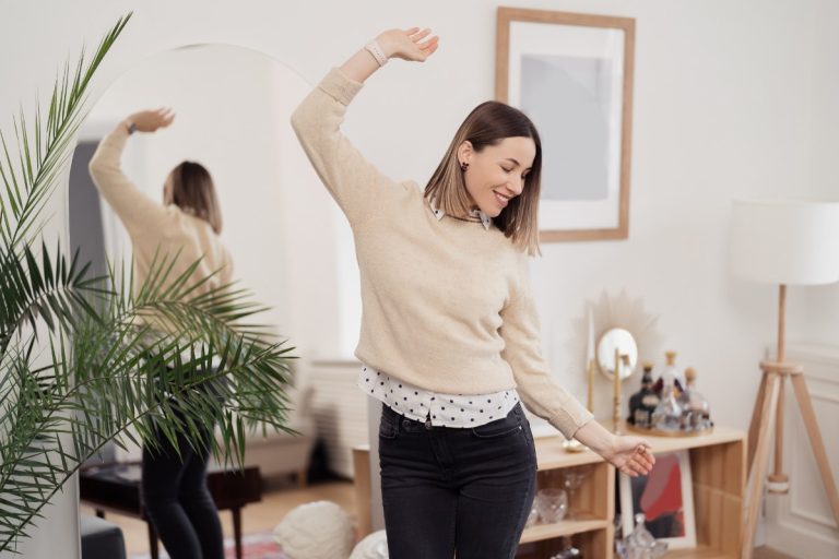 Adulte suit un cours de danse dans un studio lumineux, concentré sur les mouvements du professeur