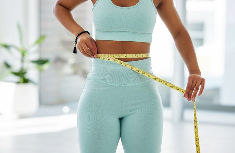 Une femme sportive mesurant sa taille et constate qu'elle a grossi