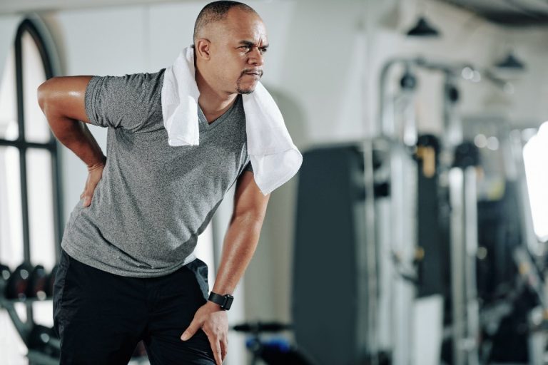Un homme dans la salle de sport, atteint d'une hernie discale