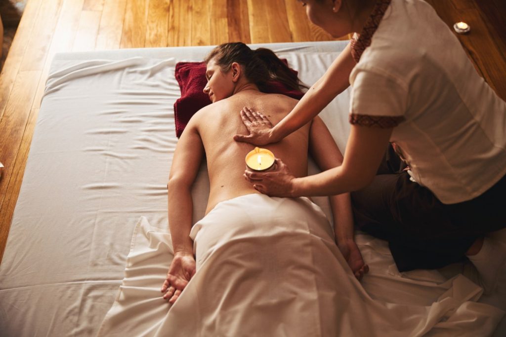 Massage de dos d'une femme avec une bougie