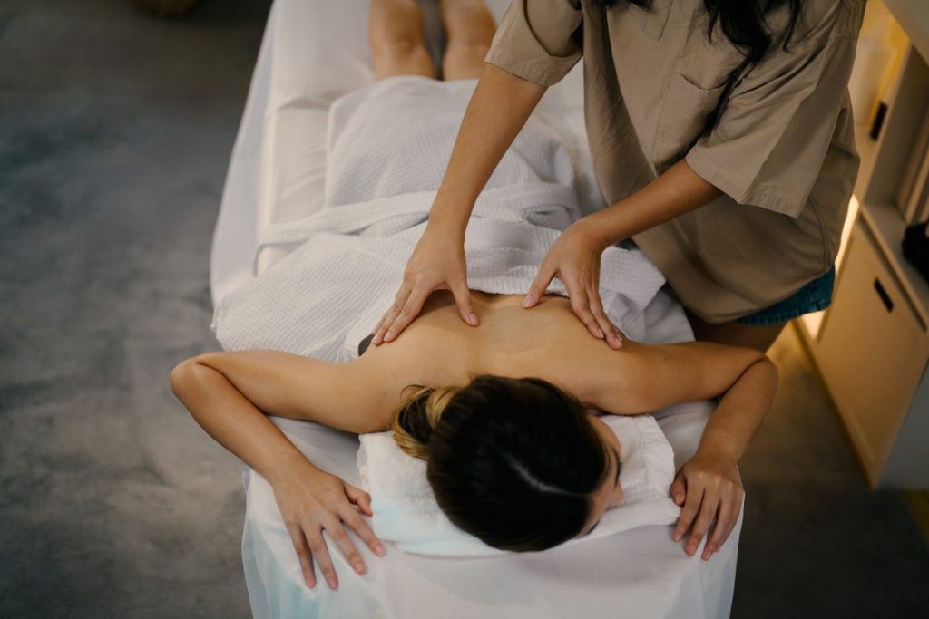 Une femme couvert par une serviette, qui reçoit un massage