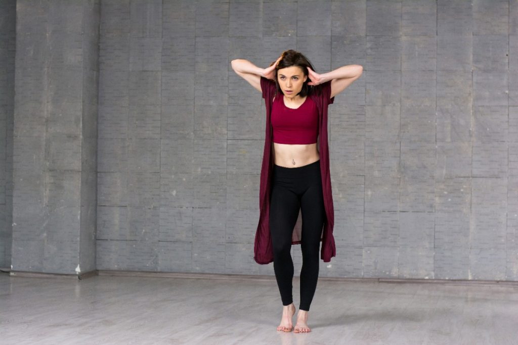 Une femme qui danse et pose les mains derrière la tête