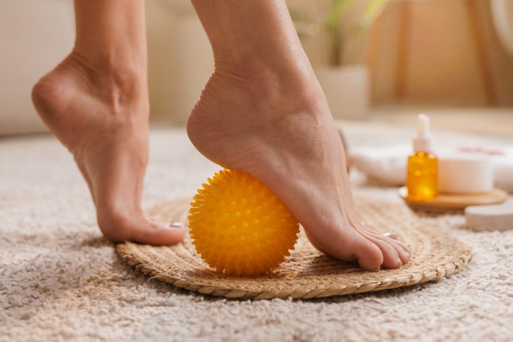 Massothérapie de pieds nus sur une balle de massage jaune