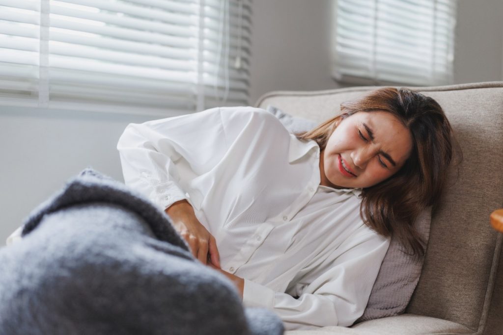 Une femme allongée sur le canapé avec un douleur au ventre