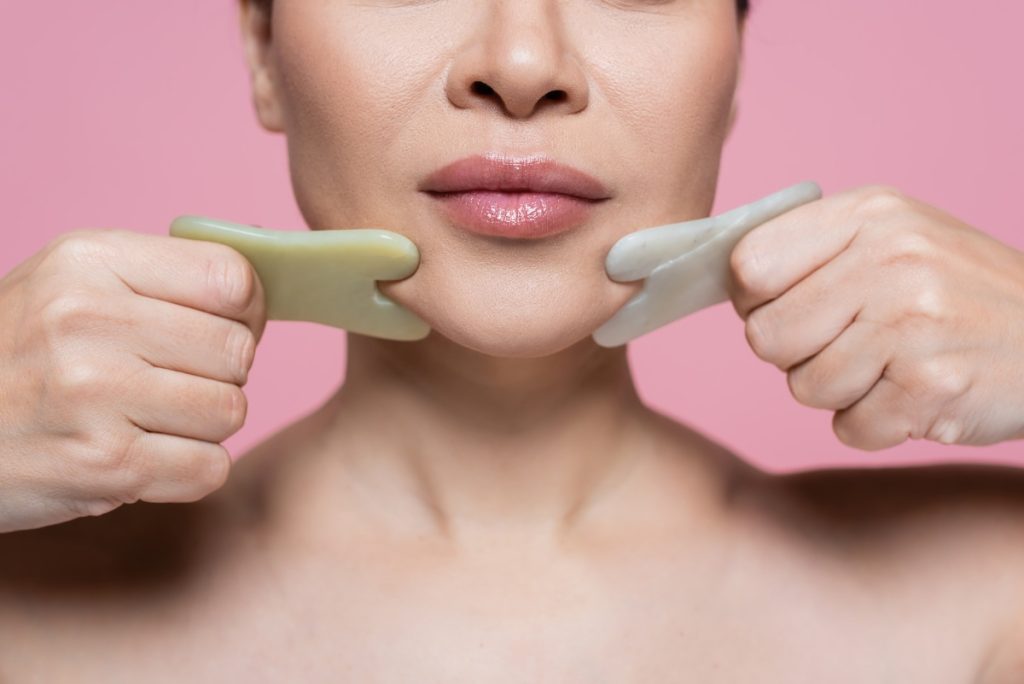 Une femme massant son visage avec du gua sha