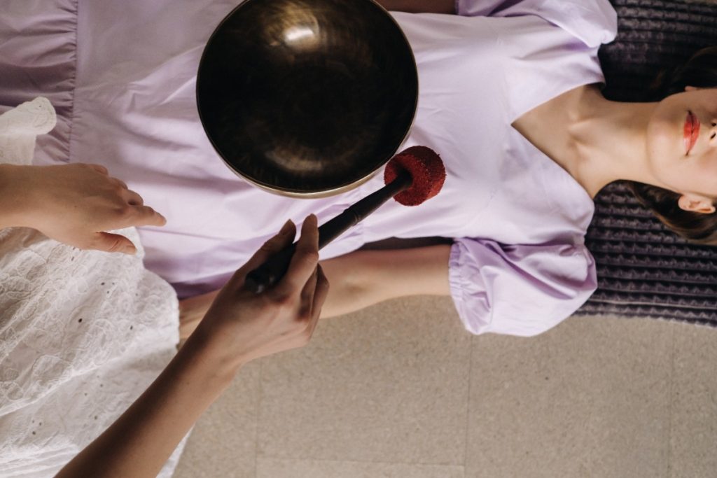 Une femme qui reçoit un traitement de thérapie avec un bol tibétain