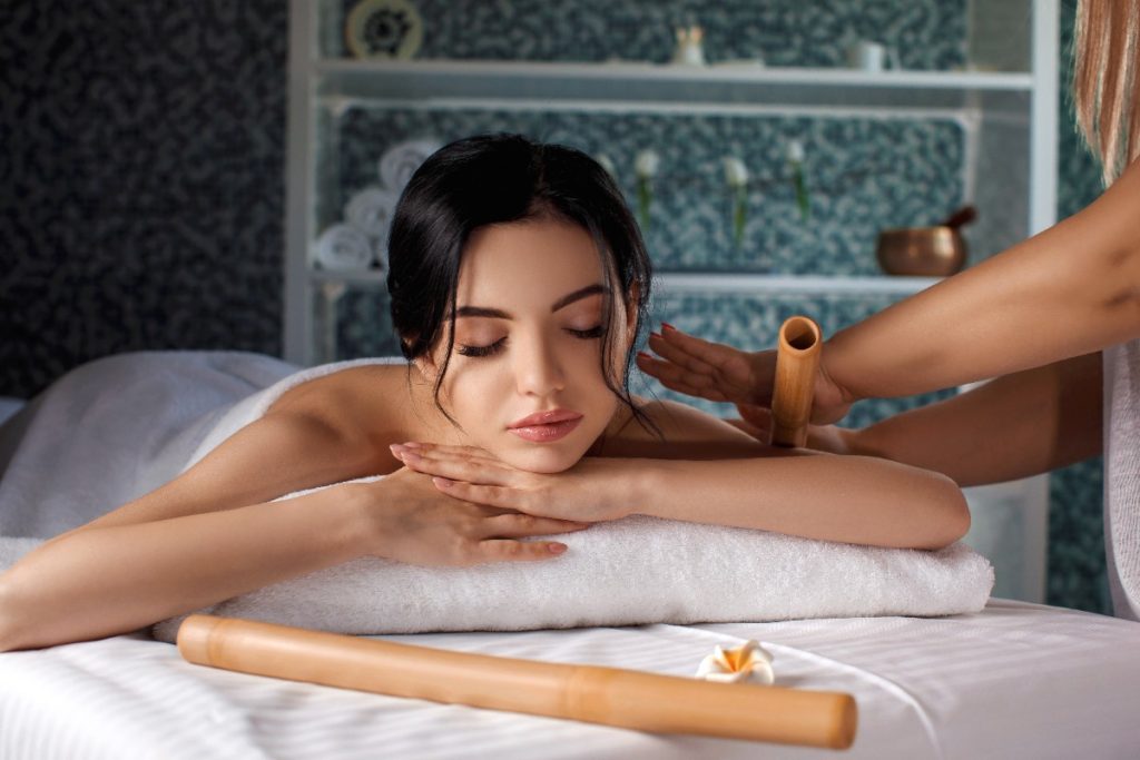 Un professionnel utilisant un bâton en bambou pour masser le bras d'une femme